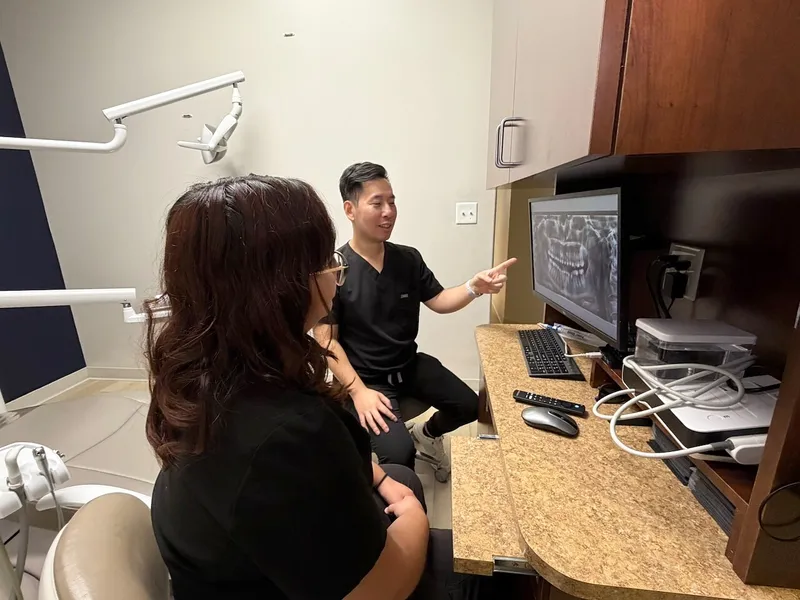 Dr. Tam reviews X-rays on the monitor with a patient at the consult desk