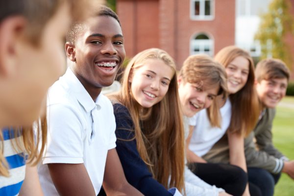 Group,Of,Teenage,Students,Sitting,Outside,School,Buildings